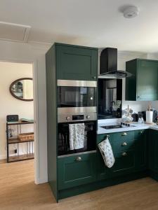 a kitchen with green cabinets and a stove top oven at Quality Court in Langton Matravers
