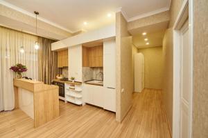 cocina con armarios blancos y suelo de madera en Apartment by the river, en Tiflis