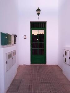 una puerta verde en una habitación blanca con suelo de ladrillo en Loft valentina en Playa Blanca
