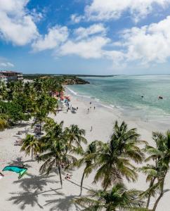 a beach with palm trees and people in the water at Hotel California Playa El Yaque in El Yaque +98 photos