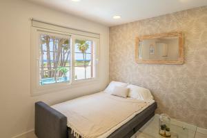 a small bed in a room with a window at Preciosos Apartamentos Reformados en Son Bou in Son Bou