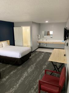 ein Hotelzimmer mit einem Bett und einem roten Stuhl in der Unterkunft ROYALINN in Elizabethtown