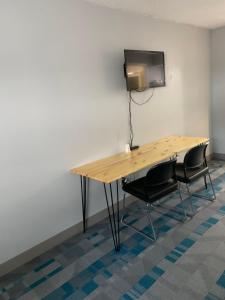 a wooden table with two chairs and a television on a wall at ROYALINN in Elizabethtown