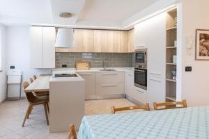 Una cocina con gabinetes blancos y una mesa con sillas. en CASA BEBA - Agenzia Dolomiti Affitti, en Cavalese 24 fotos más