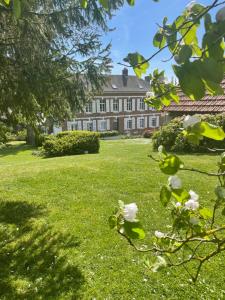 a house with a yard with green grass and flowers at Le Logis d’Anne-Sophie in Chuignolles