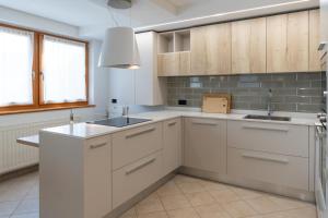 Una cocina con gabinetes blancos y un fregadero. en CASA BEBA - Agenzia Dolomiti Affitti, en Cavalese