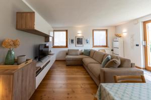 un soggiorno con un divano e una TV di CASA BEBA - Cavalese Olimpiadi 2026 Dolomiti Affitti a Cavalese