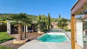 una piscina con palmeras y una casa en Les chambres du Bonheur en Fontaine-sous-Jouy