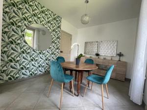 a dining room with a wooden table and blue chairs at Le Pavillon de la mare in Avrainville