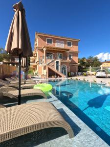 a pool with chairs and an umbrella next to a building at Studios Pantelis Corfu in Ýpsos