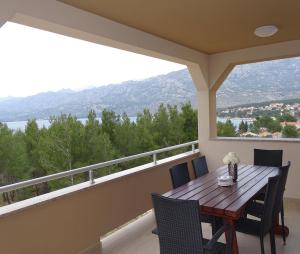 a porch with a wooden table and chairs on a balcony at Holiday house Rončević 50 m from sea A1 in Jasenice