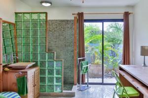 a kitchen with green glass block walls and a sliding door at Magnifique Villa Vue Mer exceptionnelle - Ireina in Punaauia