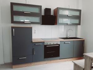 a kitchen with gray cabinets and a stove top oven at Nordunterkunft in Neumünster