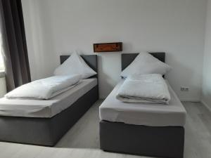 2 camas con sábanas blancas y almohadas en una habitación en Nordunterkunft, en Neumünster