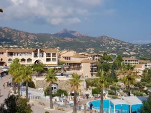 a resort with a pool and palm trees and mountains at Cap Esterel face à la mer Agay St Raphael in Drammont