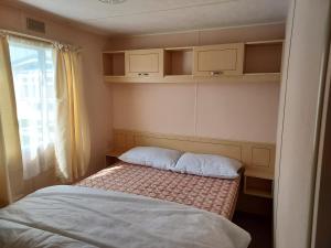 a small bedroom with a bed and a window at 8 Berth The Chase Ingoldmells Sahara Super in Ingoldmells
