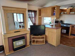 a kitchen with a fireplace and a television in it at 8 Berth The Chase Ingoldmells Sahara Super in Ingoldmells