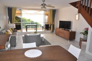 a living room with a dining table and a television at Appartement standing 2 chambres vue mer RES TAHIRI 3 in Punaauia
