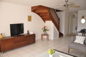 a living room with a television and a staircase at Appartement standing 2 chambres vue mer RES TAHIRI 3 in Punaauia