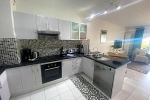 Una cocina con gabinetes blancos y una encimera negra. en Grand Studio Les Horizons Papeete, en Papeete
