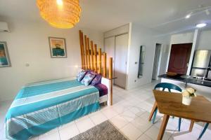 a bedroom with a bed and a table and a kitchen at Grand Studio Les Horizons Papeete in Papeete