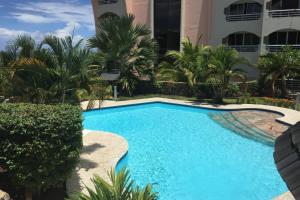 a swimming pool in front of a building with palm trees at Grand Studio Les Horizons Papeete in Papeete