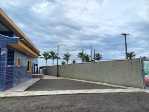 a fence next to a building with palm trees at Pousada Ohana Beach in Mongaguá +5 photos