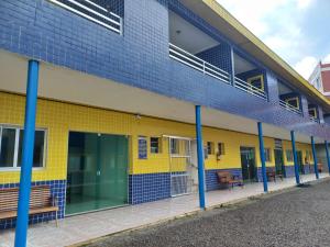 a blue and yellow building with benches on the side at Pousada Ohana Beach in Mongaguá