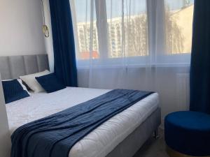 a bedroom with a bed with blue curtains and a window at Apartament 80’s in Kołobrzeg
