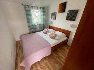 ein kleines Schlafzimmer mit einem rosa Bett mit zwei rosa Kissen in der Unterkunft Villa Ana in Vodice