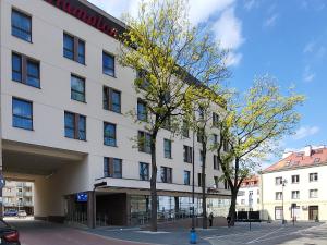 un grand bâtiment blanc avec un arbre en face dans l'établissement Apartament SixtySix 66 z kominkiem, à Białystok