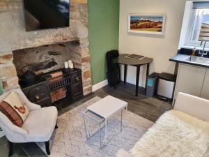 a living room with a fireplace and a tv at Oakbank Servant's Quarters in Pitlochry