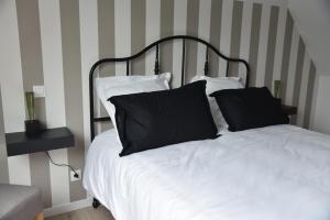 uma cama com almofadas pretas e brancas em Au Relais de Laborde em Saint-Germain-les-Vergnes