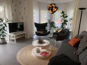 ein Wohnzimmer mit einem Sofa, Stühlen und einem TV in der Unterkunft Pool & Lake Holiday Home in Markkleeberg