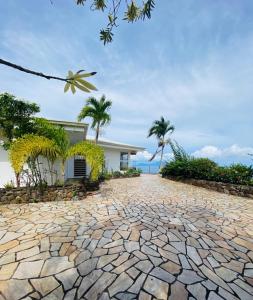 a stone driveway in front of a house with palm trees at VILLA BOUNTY AMAZING OCEAN VIEW in Punaauia