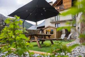 a wooden picnic table with an umbrella in a yard at Maison de village - Les Voûtes Blanches - Serre Chevalier 1350 in Saint-Chaffrey