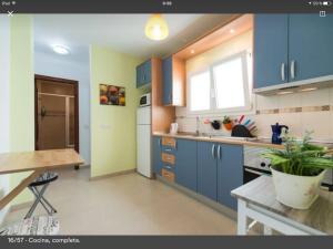 Apartamento Playa Las Canteras في لاس بالماس دي غران كاناريا: مطبخ فيه دواليب زرقاء وطاولة فيه