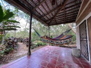 eine Hängematte auf einer Veranda eines Hauses in der Unterkunft Jungle Cabins El Escondido in Muy Muy