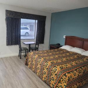 a hotel room with a bed and a table and a window at Economy inn in Corning