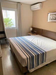 um quarto com uma cama com um cobertor listrado azul e branco em Hotel Sol By MRHotelaria em Curitiba