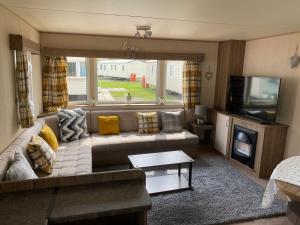 a living room with a couch and a television at Haggerston Castle 6 Berth Caravan - Lakeside North 23 in Cheswick