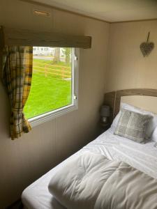 a bedroom with a bed and a window with a green field at Haggerston Castle 6 Berth Caravan - Lakeside North 23 in Cheswick