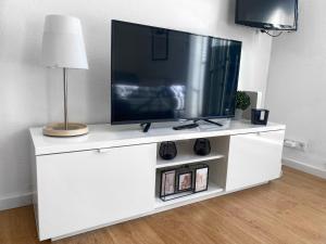 un centro di intrattenimento bianco con TV a schermo piatto di Schickes Appartement in Wuppertal-Ronsdorf Whg. 66 a Wuppertal