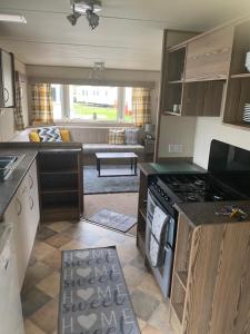 a kitchen with a stove and a living room at Haggerston Castle 6 Berth Caravan - Lakeside North 23 in Cheswick