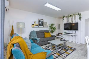a living room with a blue couch and a tv at Vilar do Jardim - Terrace and Pool - Vilamoura in Quarteira