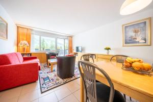 a living room with a table and a red couch at Chasa Plavna 403 in Vulpera