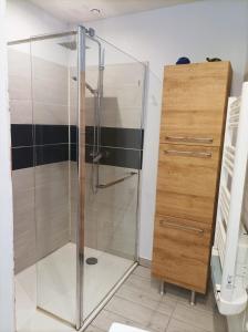 un baño con ducha de cristal junto a un armario de madera en Agréable maison de ville tout confort, en Loudun