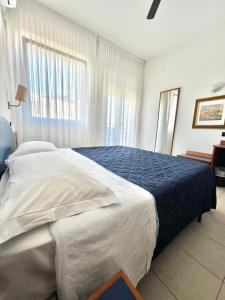a bedroom with a large bed with a blue blanket at Hotel B&B Montecarlo in Milano Marittima