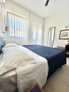 een slaapkamer met een groot bed en een blauwe deken bij Hotel B&B Montecarlo in Milano Marittima