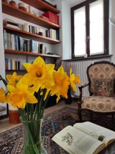 un vase rempli de fleurs jaunes à côté d'un livre dans l'établissement La Foresteria dei Baldi, à Pavia